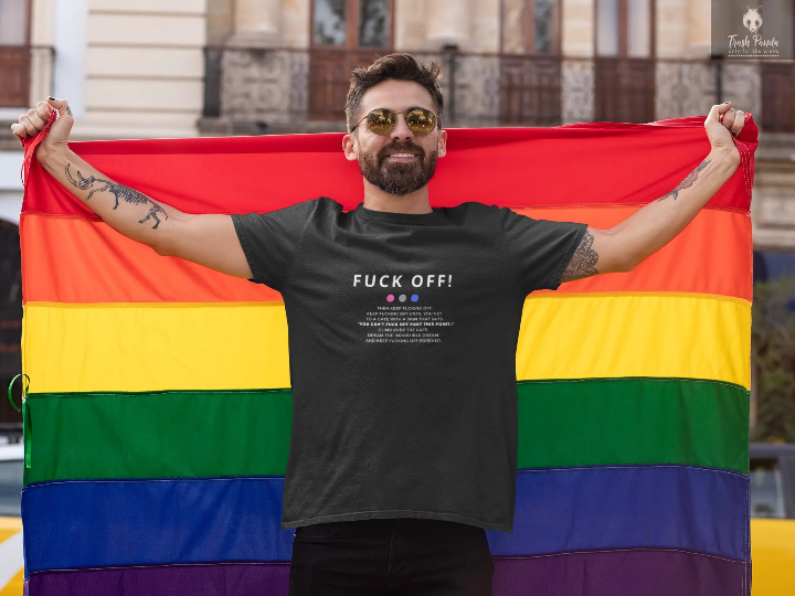 Man with a rainbow flag wearing a black tshirt that says Fuck off and more 