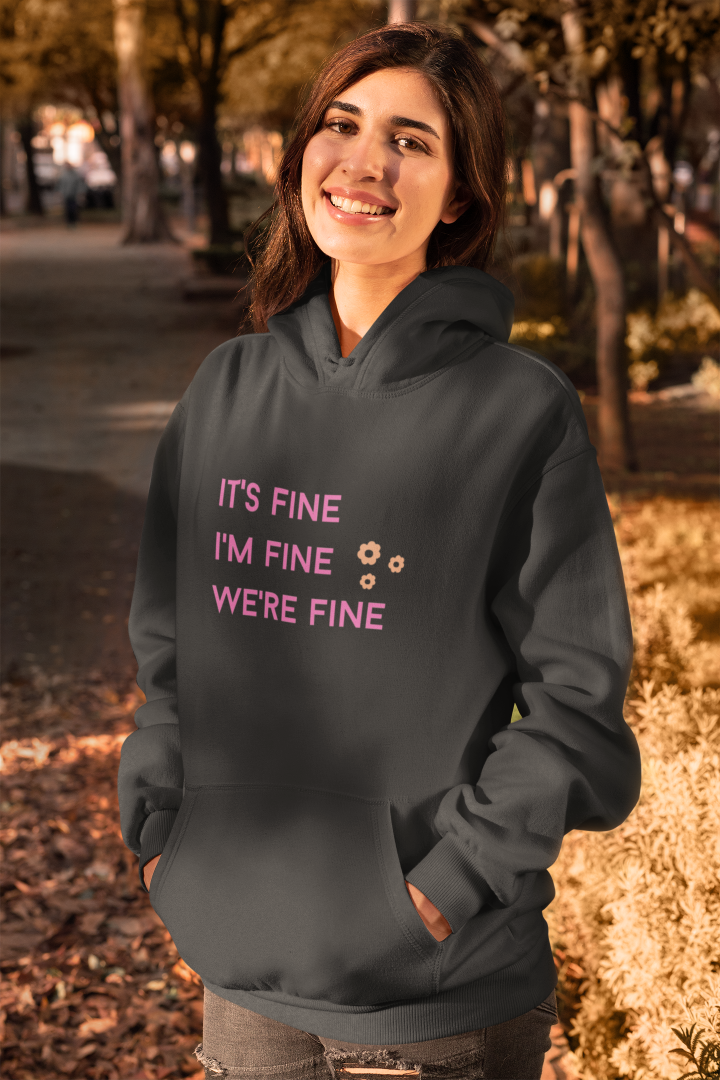 model is wearing a black hoodie with the words it's fine i'm fine we're fine