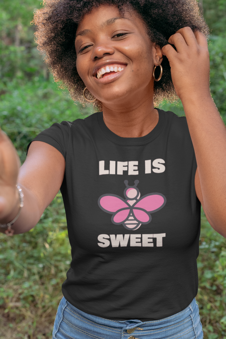 model is wearing a black t shirt with a graphic of a pink bee and the words life is sweet